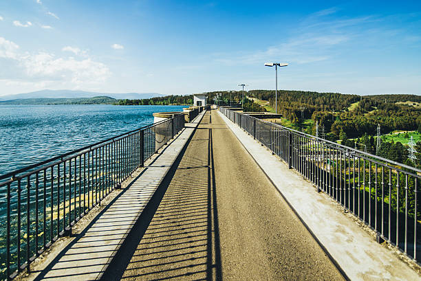 A view of a dam with water on one side and a green valley on the other.
