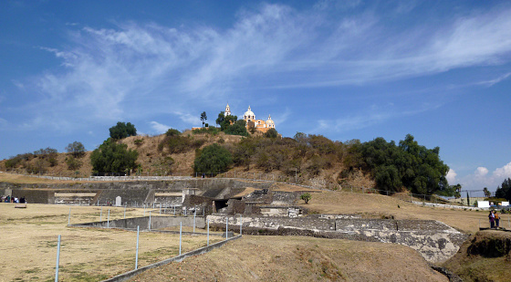 Cholula, Puebla, Mexico - January 04, 2013: Wide view of the Great Pyramid of Cholula complex showing the part excavated and the part that remains as an artificial hill with trees. At the top the church of the Shrine of Our Lady of Remedies.