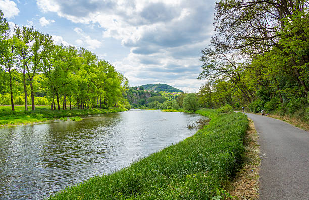 istock Summer landscape with green grass, road, river and clouds 538642866