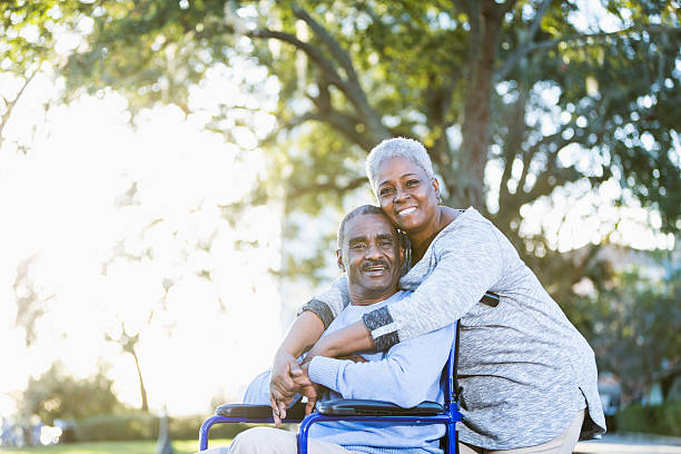 senior pareja afroamericana, hombre en silla de ruedas - couple dependency standing men fotografías e imágenes de stock