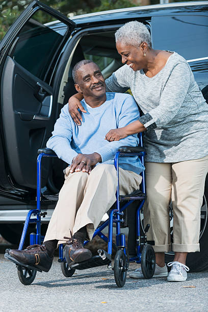 senior pareja de hombre en silla de ruedas al lado del coche - couple dependency standing men fotografías e imágenes de stock