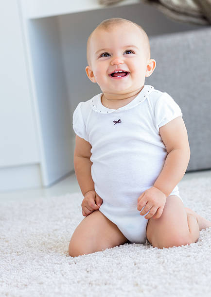 istock Cute cheerful baby sitting on carpet 538644055