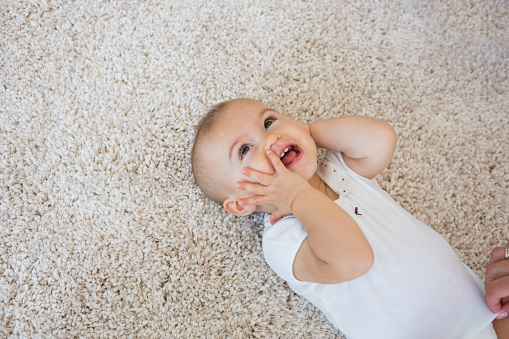 High angle view of a happy cute baby lying on carpet at home