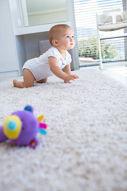 Side view of a cute baby crawling on carpet at home