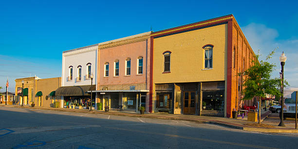 Downtown City Street Storefronts at dusk on a quiet street in a small Georgia town. The scene includes a several shops in the evening light against a deep blue sky. The street and parking spaces are empty. city street street corner tree stock pictures, royalty-free photos & images