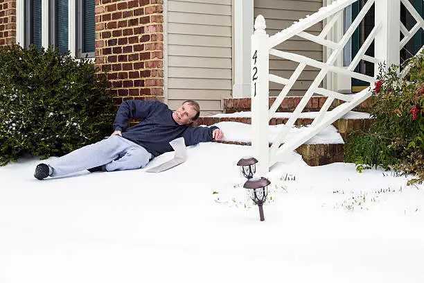 Photo of Senior adult male grimaces in pain in the snow.