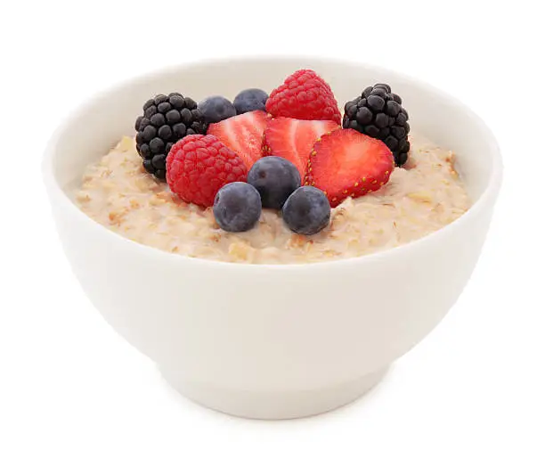 Oatmeal and fresh strawberry, blueberries, raspberries and blackberries in a Bowl isolated on white (excluding the shadow)