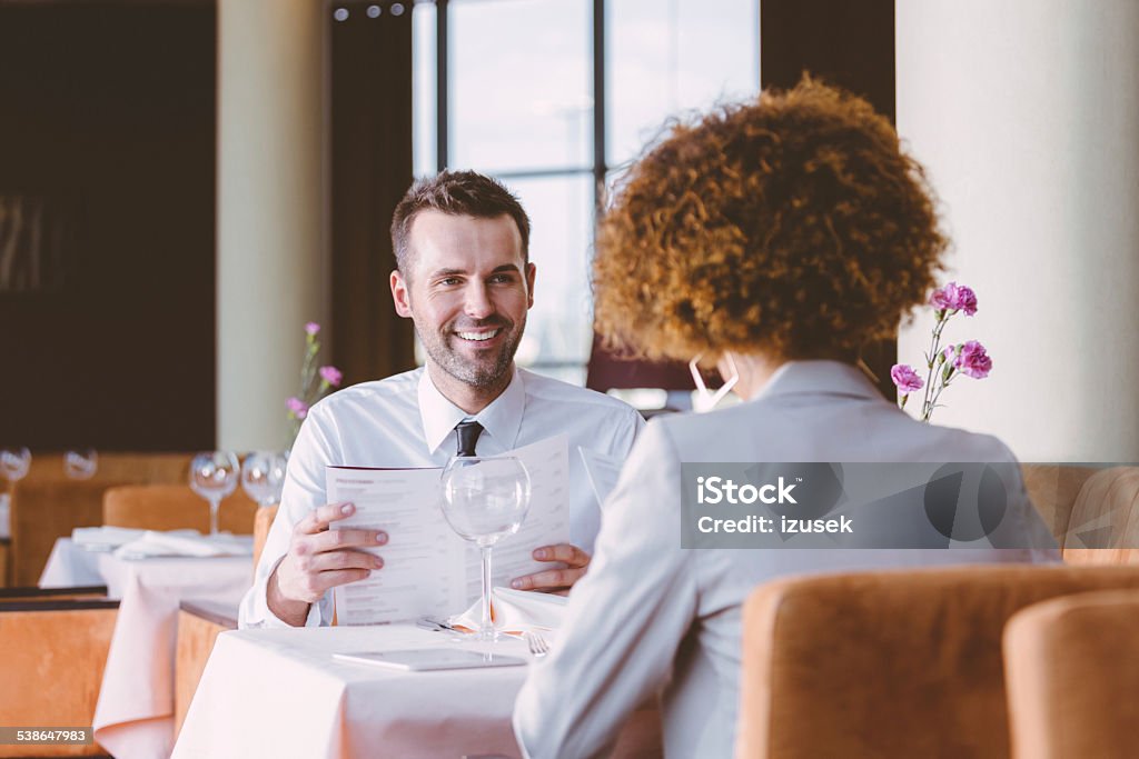 Two business people on lunch Businesswoman and businessman having lunch in restaurant, reading menu. Restaurant Stock Photo