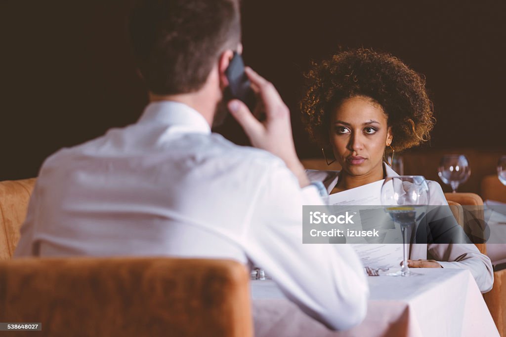 Two business people on lunch Businesswoman and businessman having lunch in restaurant, afro american woman reading menu and man talking on phone.  Bar - Drink Establishment Stock Photo