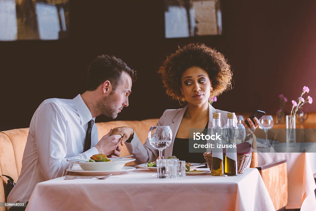 Flirting couple on lunch Cheerful businesswoman and businessman flirting during lunch in the restaurant, sitting at the table, man holding woman's hand. 2015 Stock Photo
