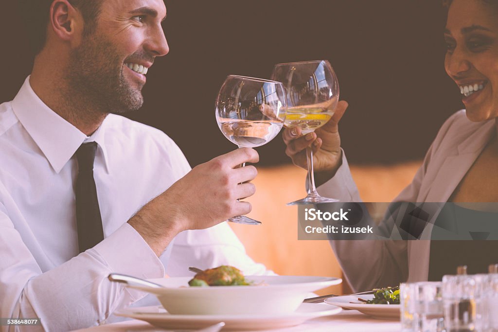 Businessman and businesswoman on lunch Cheerful businesswoman and businessman having lunch in the restaurant, toasting with wine glasses. 2015 Stock Photo
