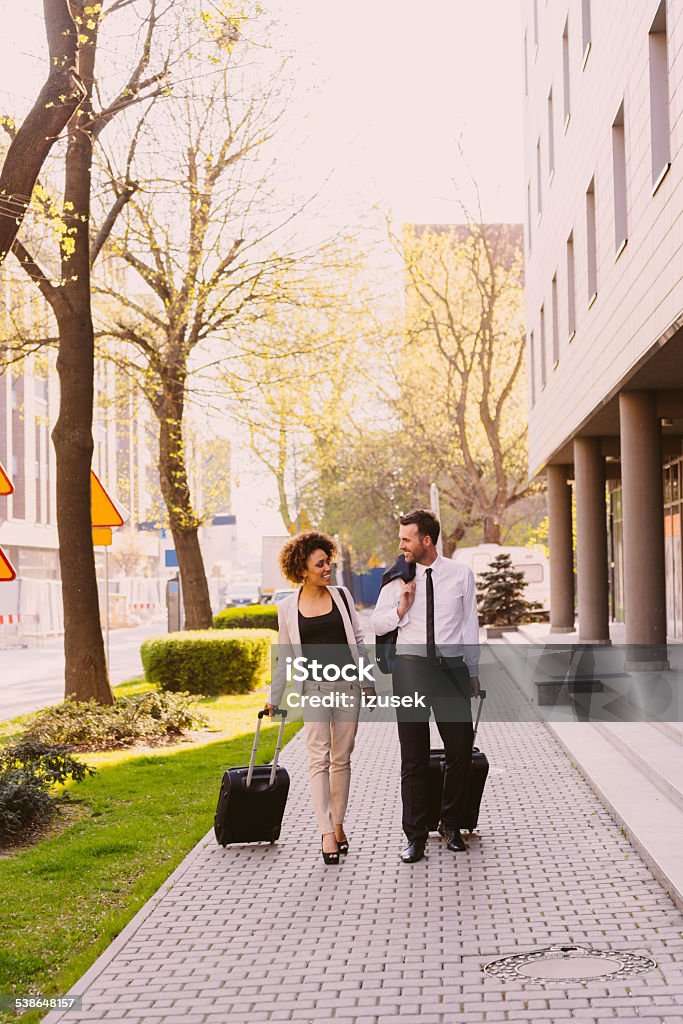 Businessman and businesswoman on business travel Businessman and businesswoman walking on the sidewalk carrying suitcases.  African Ethnicity Stock Photo