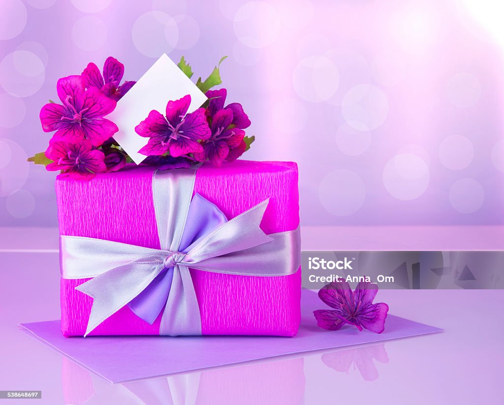 Pink gift box with greeting card Picture of pink gift box with purple silk ribbon, beautiful violet wild flowers bouquet, white blank greeting card, beautiful romantic still life, blur background, happy mothers day, reflection 2015 Stock Photo