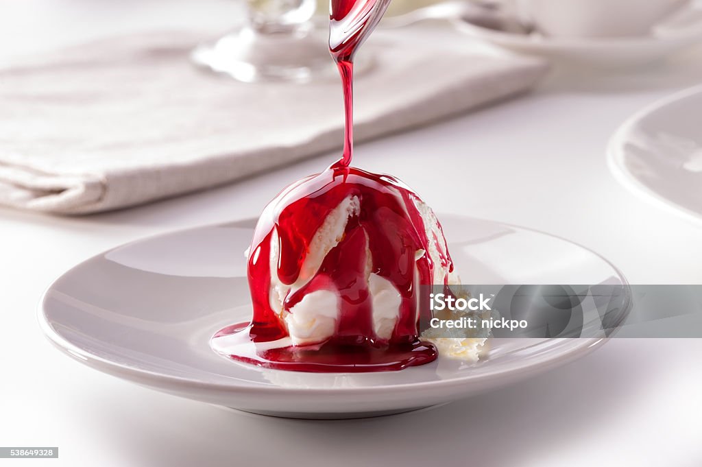 Boule de glace à la sauce de baies à verser de la cuillère gros plan - Photo de Crème glacée libre de droits