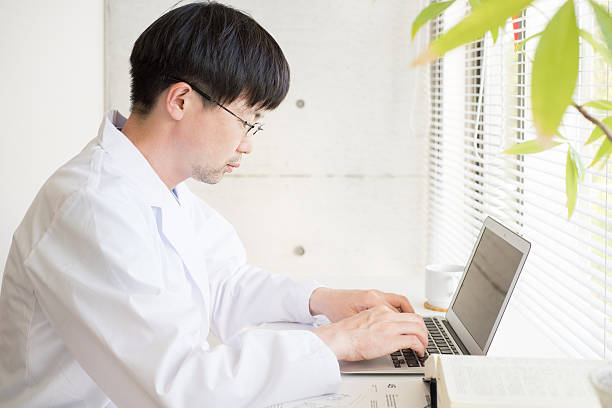 istock Man of a white robe doing desk work by window 538649974