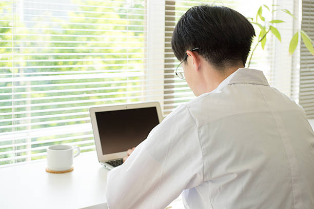 istock Man of a white robe doing desk work by window 538650078