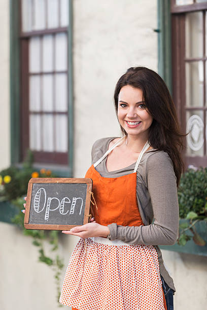istock Woman wearing apron holding OPEN sign 538650365