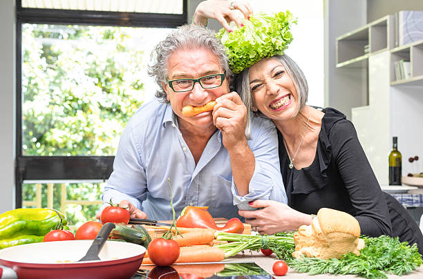 casal sénior a divertir-se na cozinha a cozinhar comida saudável juntos - cooking senior adult healthy lifestyle couple imagens e fotografias de stock