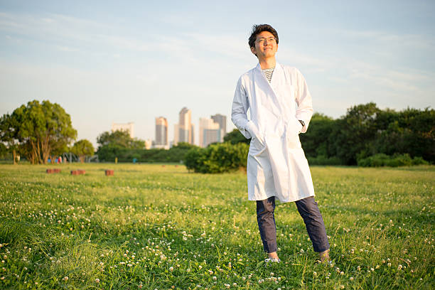 homme (groupe de bâtiment, parc, du gazon) décorées dans le peignoir blanc - scientist male young adult doctor photos et images de collection