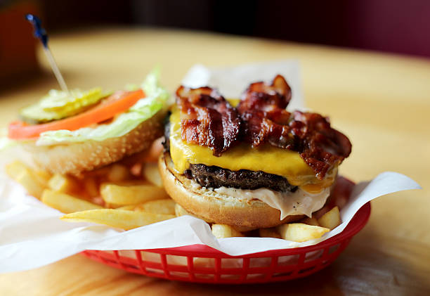 Bacon Cheeseburger with Fries Delicious flame broiled hamburger on bun topped with melted cheddar cheese and crispy brown bacon bacon cheeseburger stock pictures, royalty-free photos & images
