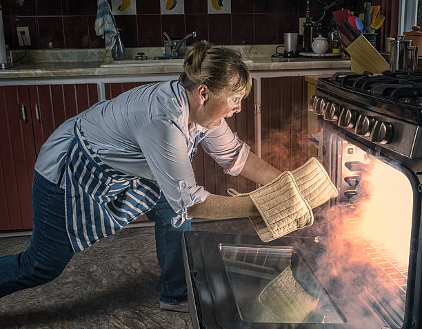 Woman  Shocked  at Oven Fire While Cooking in the Kitchen. stock photo