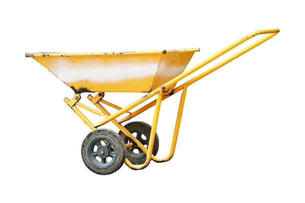 Old, rusty garden wheelbarrow in a sunlit rural yard, well-used and weathered