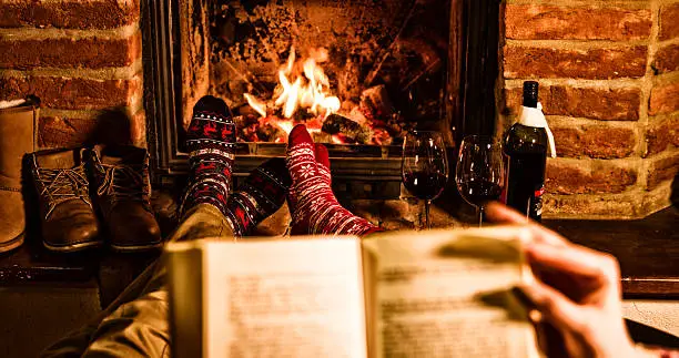 Photo of Couple with book resting by fireplace during Xmas