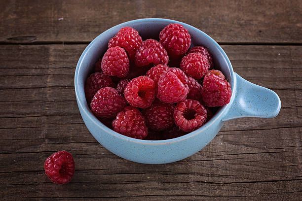 istock Ripe fresh raspberries in bowl on wooden rustic background 538658178