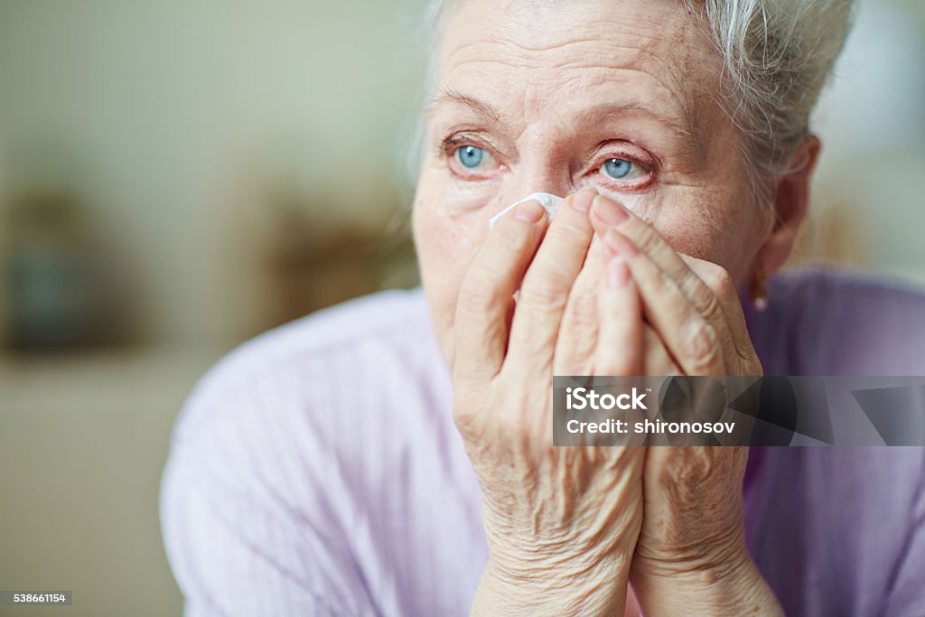 Sadness Sad senior woman wiping her tears Teardrop Stock Photo