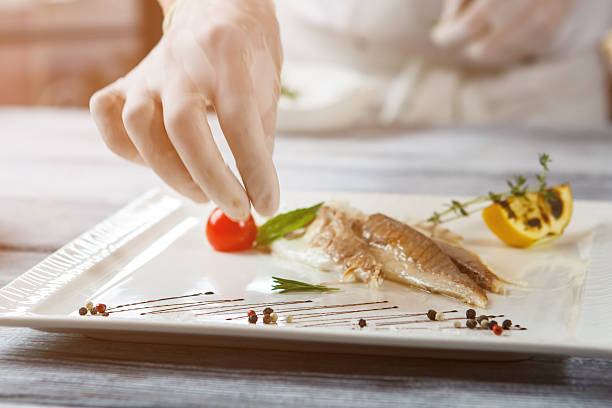 Hand over plate with fish.