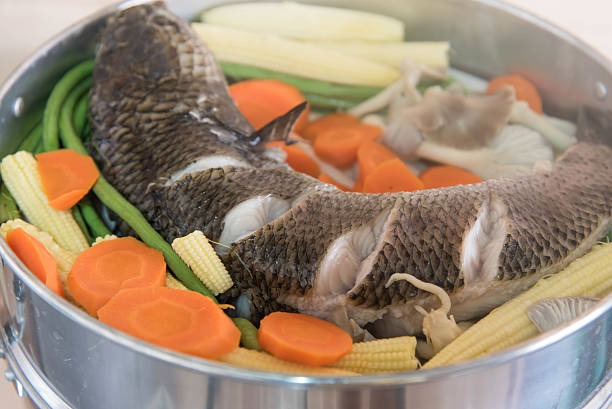 Snake head fish and vegetable are steamed in stainless steamer pot  on the stove