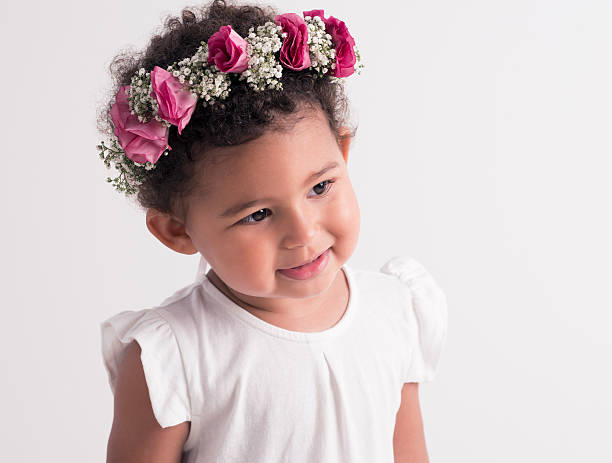 Portrait of smiling little girl with red rose flower wreath in her hair. Isolated on white image.