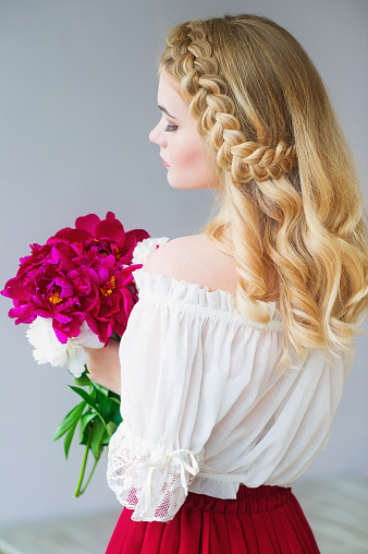 Beautiful woman rustic style with braids holding peonies