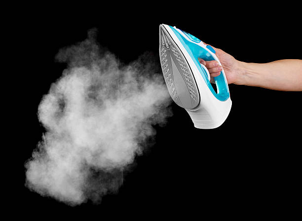 istock Steam iron in female hand isolated on black background. 538674828