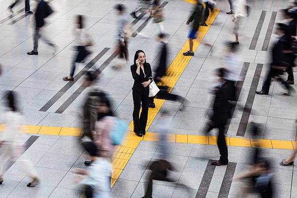 japonés mujer hablando por el teléfono móvil rodeado de los trabajadores - blurred motion motion group of people crowded fotografías e imágenes de stock