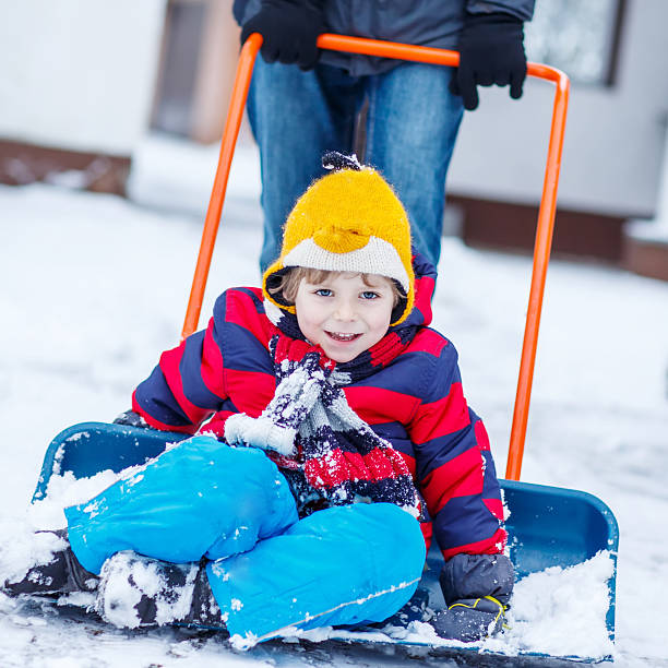 istock Funny kid boy having fun with riding on snow shovel, 538681753