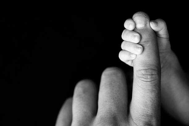 Newborn Baby's Hand Gripping Dad's Finger stock photo