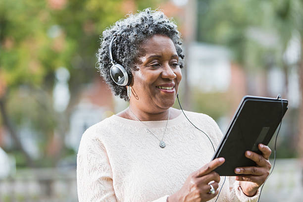 sênior mulher negra usando tablet digital - women book mature adult reading - fotografias e filmes do acervo