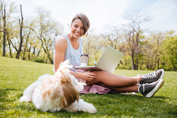 istock Young pretty girl sitting and holding computer in the park 538686592