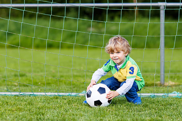 два маленький брат и сестра мальчики играют в футбол футбола на поле - playing field goalie soccer player little boys стоковые фото и изображения