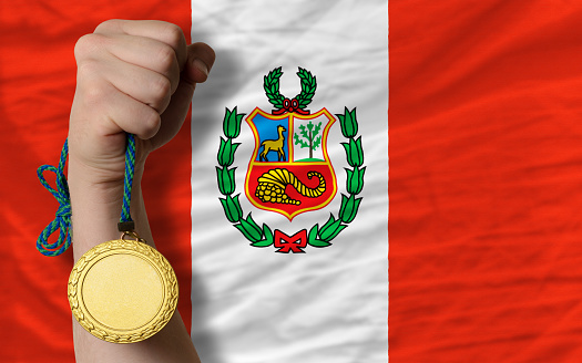 Winner holding gold medal for sport and national flag of peru