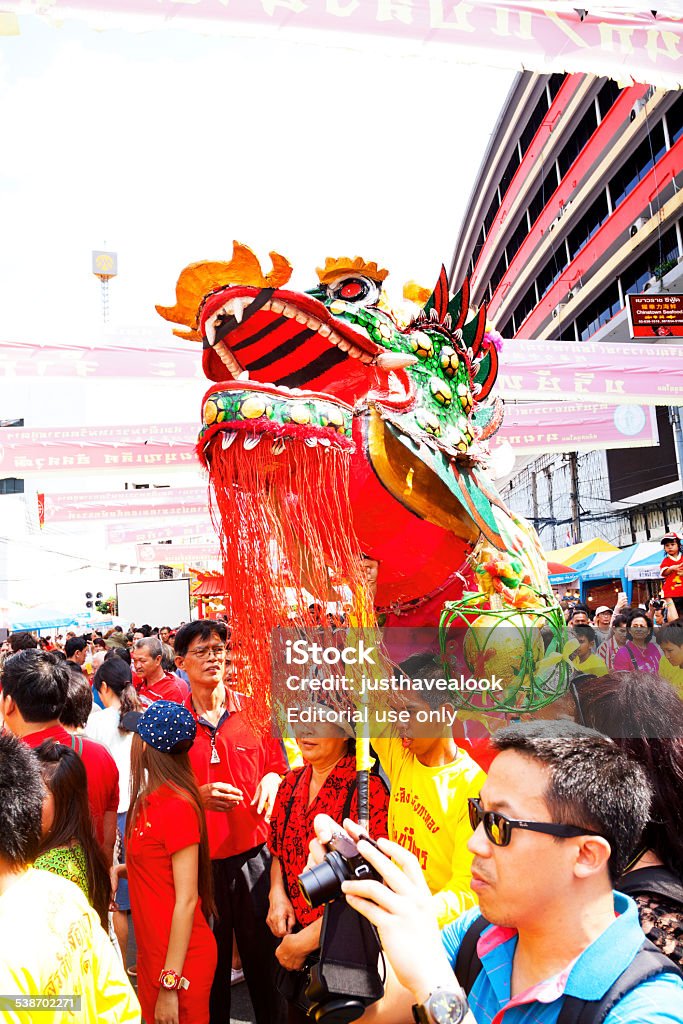 Green and red chinese dragon Bangkok, Thailand - February 19, 2015: Green and red chinese dragon and dragon dance parade at chinese new year in Yaowarat Road. Scene in Chinatown of Bangkok. Many people are in street. Man in foreground is taking photos. Above people are banners. 2015 Stock Photo
