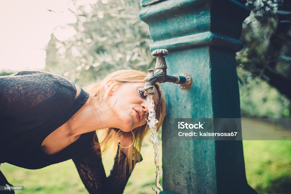 Woman drinking water from fountain Thirsty Stock Photo