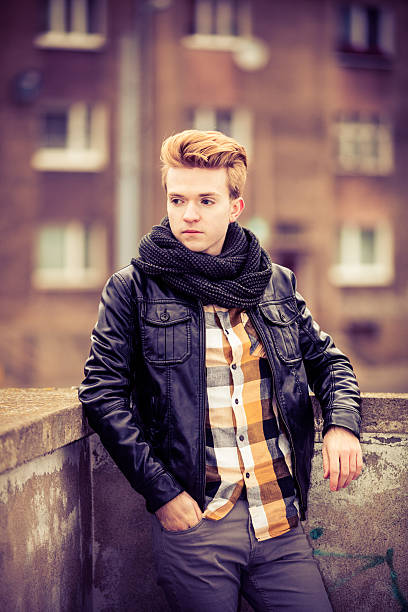 Studio portrait of a 20 year old man in a hooded shirt on a black background