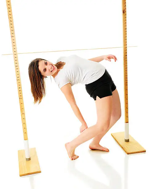 An attractive teen girl successfully backing under the limbo stick.  On a white background.