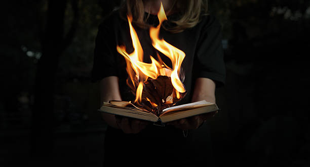 Image of book burning in woman hands in dark forest Image of book burning in woman hands in dark forest book burning stock pictures, royalty-free photos & images