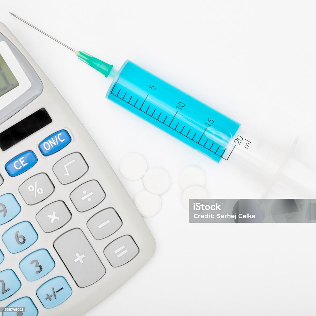 Syringe with blue liquid inside and calculator 2015 Stock Photo