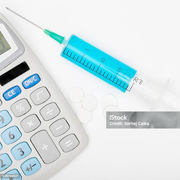 Syringe With Blue Liquid Inside And Calculator Stock Photo - Download Image Now - 2015, Addiction, Blue