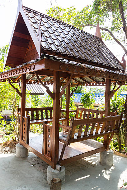 Elegant gazebo featuring intricately designed iron pillars and furniture, immersed in a vibrant floral setting with a scenic view, perfect for gatherings or peaceful moments.