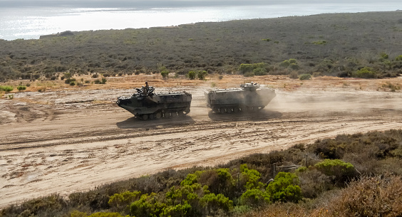 a military amphibious vehicle drives along a coastline